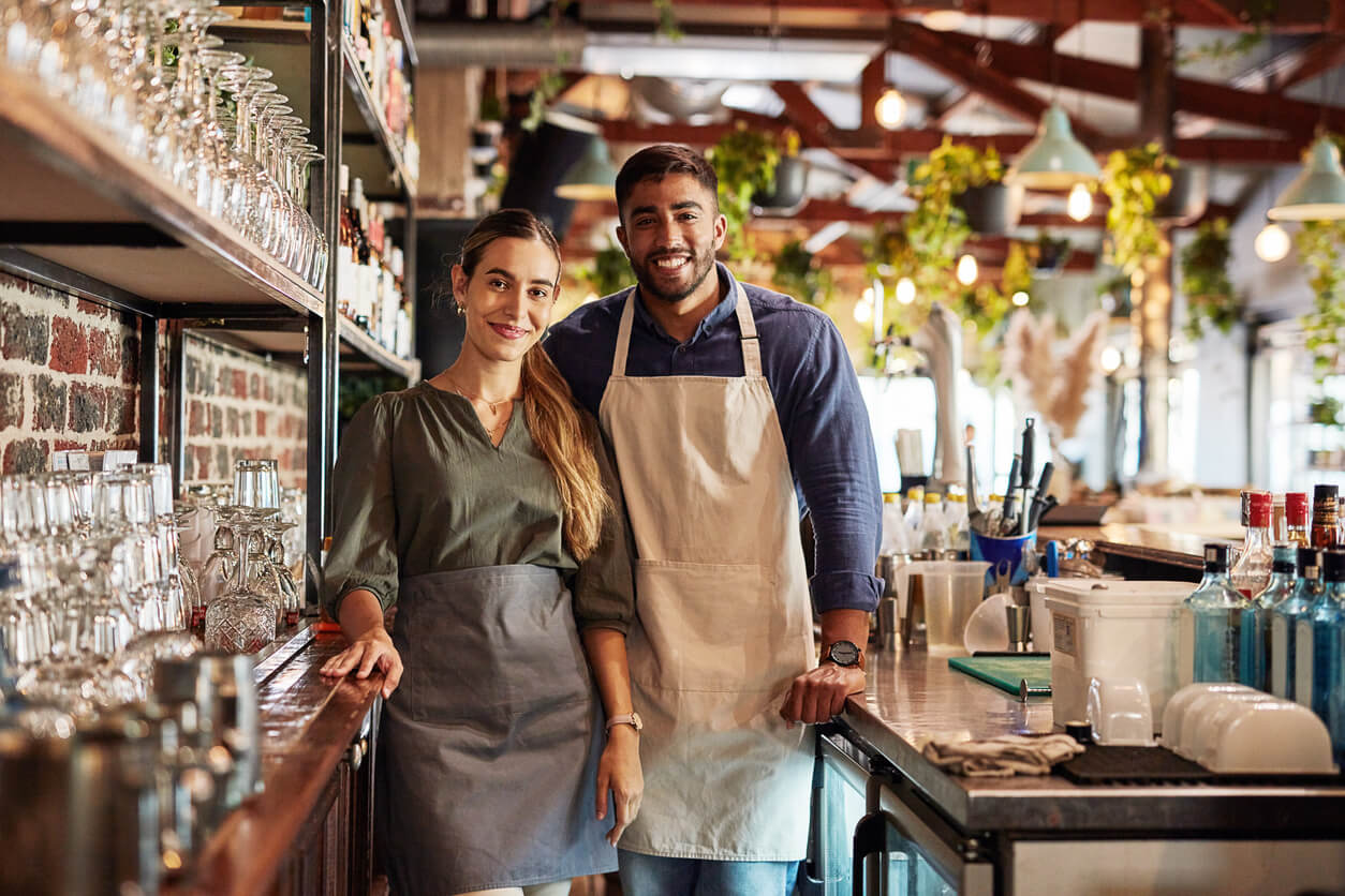 Small business, pub owner and portrait of couple, smile at cafe counter and hospitality startup investment. Success, confidence and man with woman in service industry, management and bespoke wine bar in Boston small business consulting